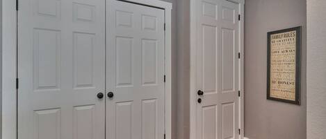 A hallway with two white double doors and a framed family rules poster on the wall.