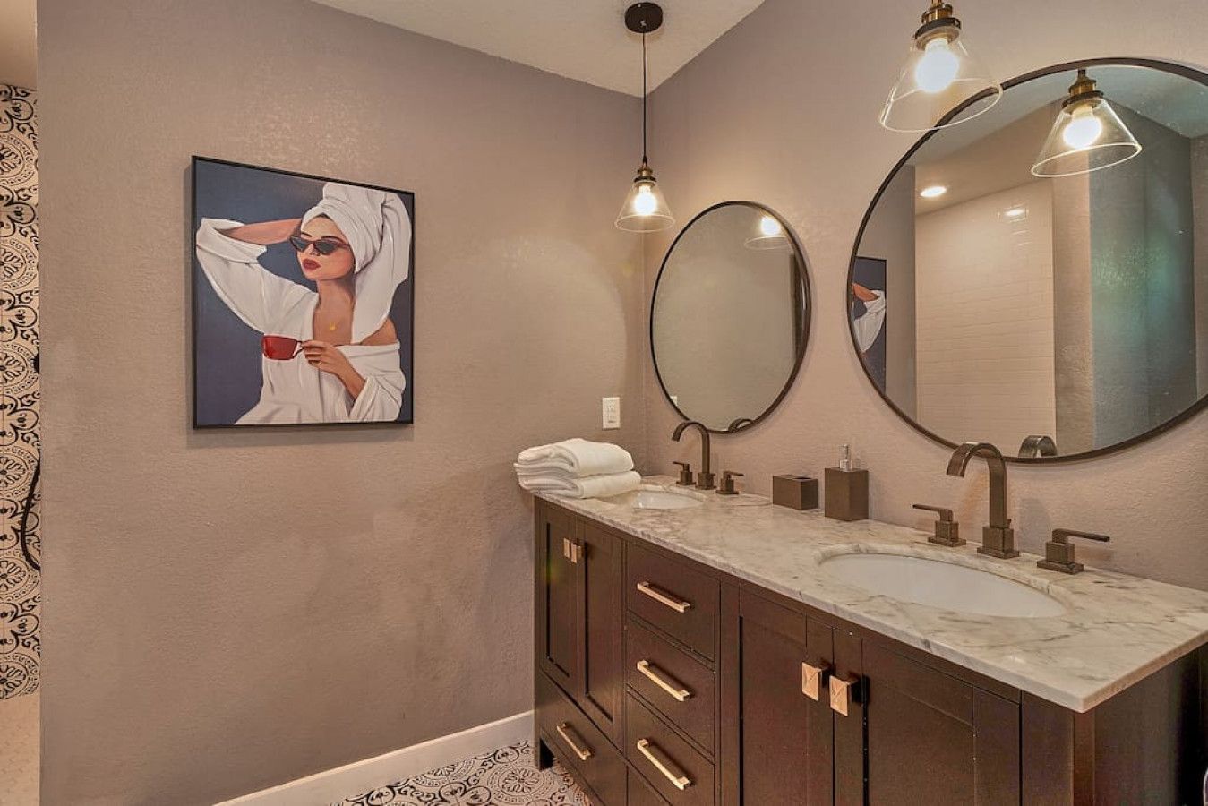 A bathroom with a marble vanity, two sinks, a large mirror, and a framed artwork on the wall.