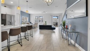 A modern kitchen with a bar area, a dining space, and a living area with a sofa.