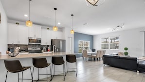 A modern kitchen with white cabinets, a central island, and bar stools.