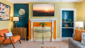 Una sala de estar con chimenea, un sofá, una mesa de centro y un televisor montado en la pared.