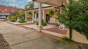 A hotel with a covered patio area, outdoor seating, and a brick facade. - The Jefferson Inn, Downtown Southern Pines, King Bed (Southern Pines)