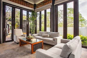 Relax in this spacious living room with a high ceiling and expansive views of the outdoors through large windows.