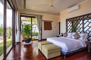 Relax in a spacious bedroom with a large bed, seating area, and potted plant, offering a comfortable retreat.