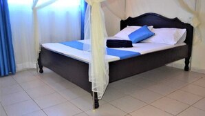 Un lit à baldaquin, avec une literie blanche et des touches de couleur bleue.