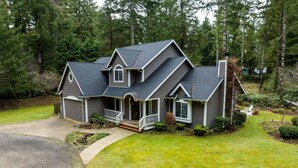 A two-story house with a front porch, a garage, and a well-maintained lawn. - New Listing! Beautiful well appointed Woahink lake area home w/ gas grill and fire pit (Florence)