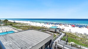 A beach view with a pool, beach umbrellas, and a clear sky.