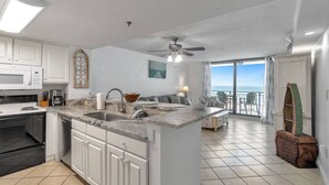 A kitchen with a central island, a dining area with a view, and a balcony with a view.