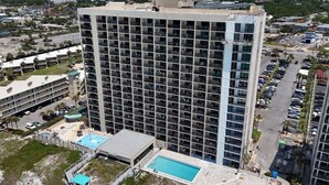 A high-rise hotel with multiple floors, a swimming pool, and a parking lot.