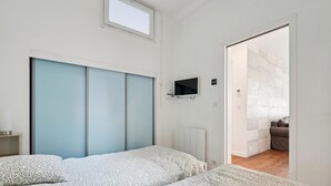 Quarto com duas camas, televisão e janela.