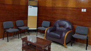 Una habitación con paneles de madera, un espejo grande y una mesa de centro de madera. Hay cuatro sillas, una de ellas un sillón de cuero.