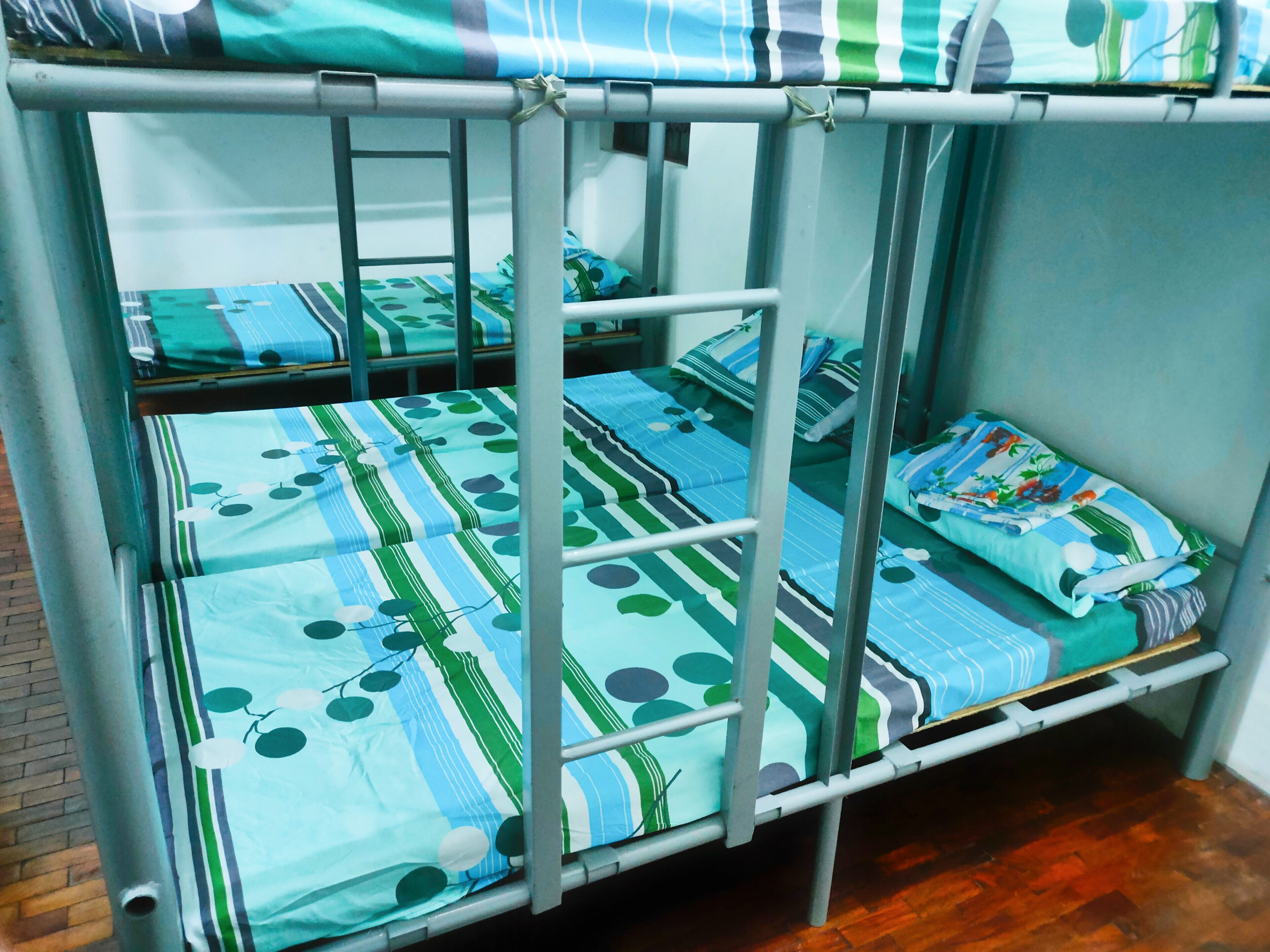 A bunk bed with multiple beds, each with a striped and polka dot patterned bedspread.