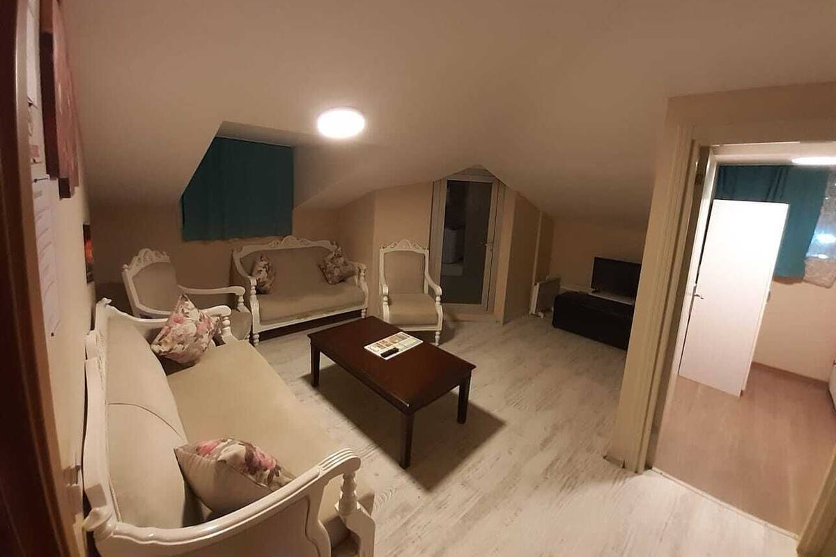 A living room with a beige sofa, two armchairs, a coffee table, and a television.