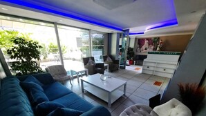 Un salon moderne avec un canapé bleu, des fauteuils blancs et une table basse.