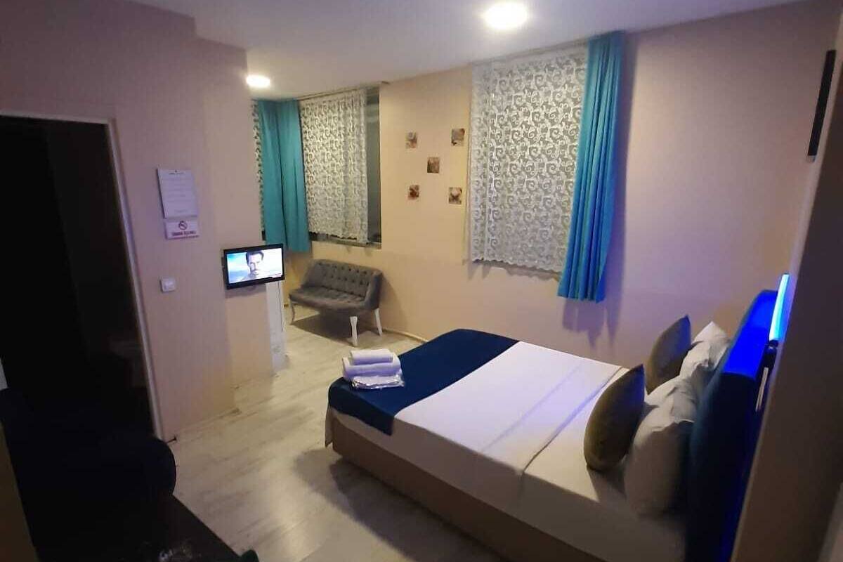 A bedroom with a bed, a chair, a TV, and a desk.