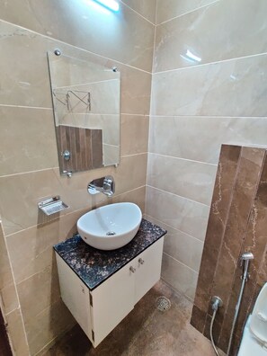 A bathroom with a white sink, a mirror, and a shower. - Hotel 56 (Amritsar)