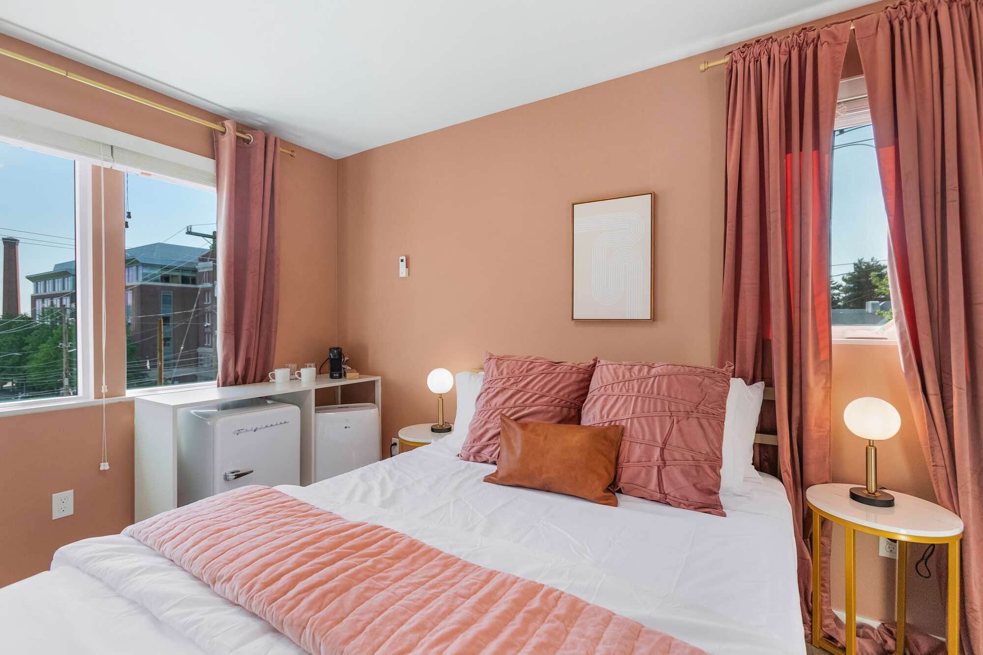 Un dormitorio con cama, mesitas de noche, un escritorio y una ventana con cortinas.