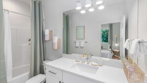 Un baño con lavamanos blanco, espejo y cortina de ducha.