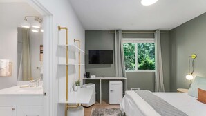 A bedroom with a bed, a desk, a TV, and a window with a view of trees. - Kurt's Sweet Suite - 84 Walkscore!! (Seattle)
