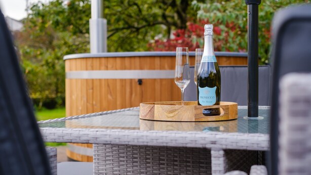 Une table en verre avec une bouteille de vin et deux verres posés sur un sous-verre en bois.