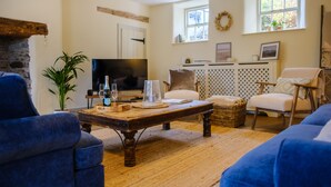 Un salon chaleureux avec une cheminée en pierre, une table basse en bois et des canapés bleus.