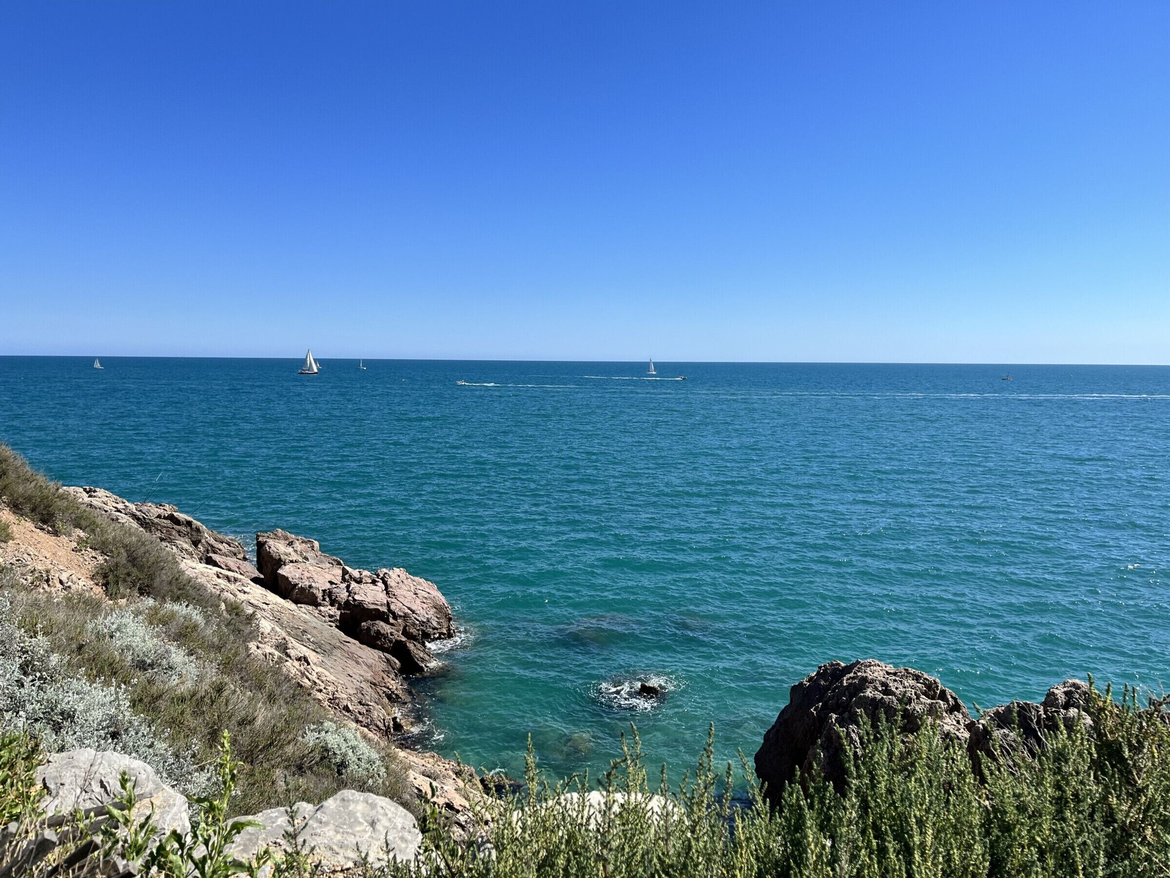 Un paysage côtier caractérisé par un terrain rocheux et une mer d’un bleu limpide.