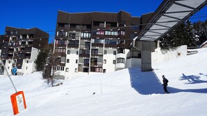 A multi-story building with balconies, a ski lift, and a skier. - Renovated 2-room apartment, ski-in/ski-out, 4 pers, WiFi (Les Menuires)