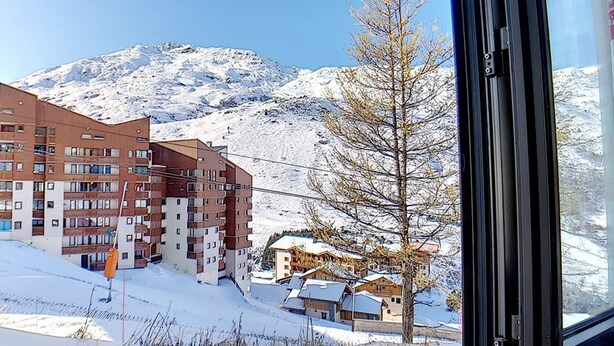 A hotel with multiple floors, a ski slope in the background, and a clear view of the mountains. - Renovated 2-room apartment, ski-in/ski-out, 4 pers, WiFi (Les Menuires)