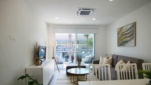Una sala de estar moderna con un sofá, una mesa de centro y un televisor sobre un mueble.