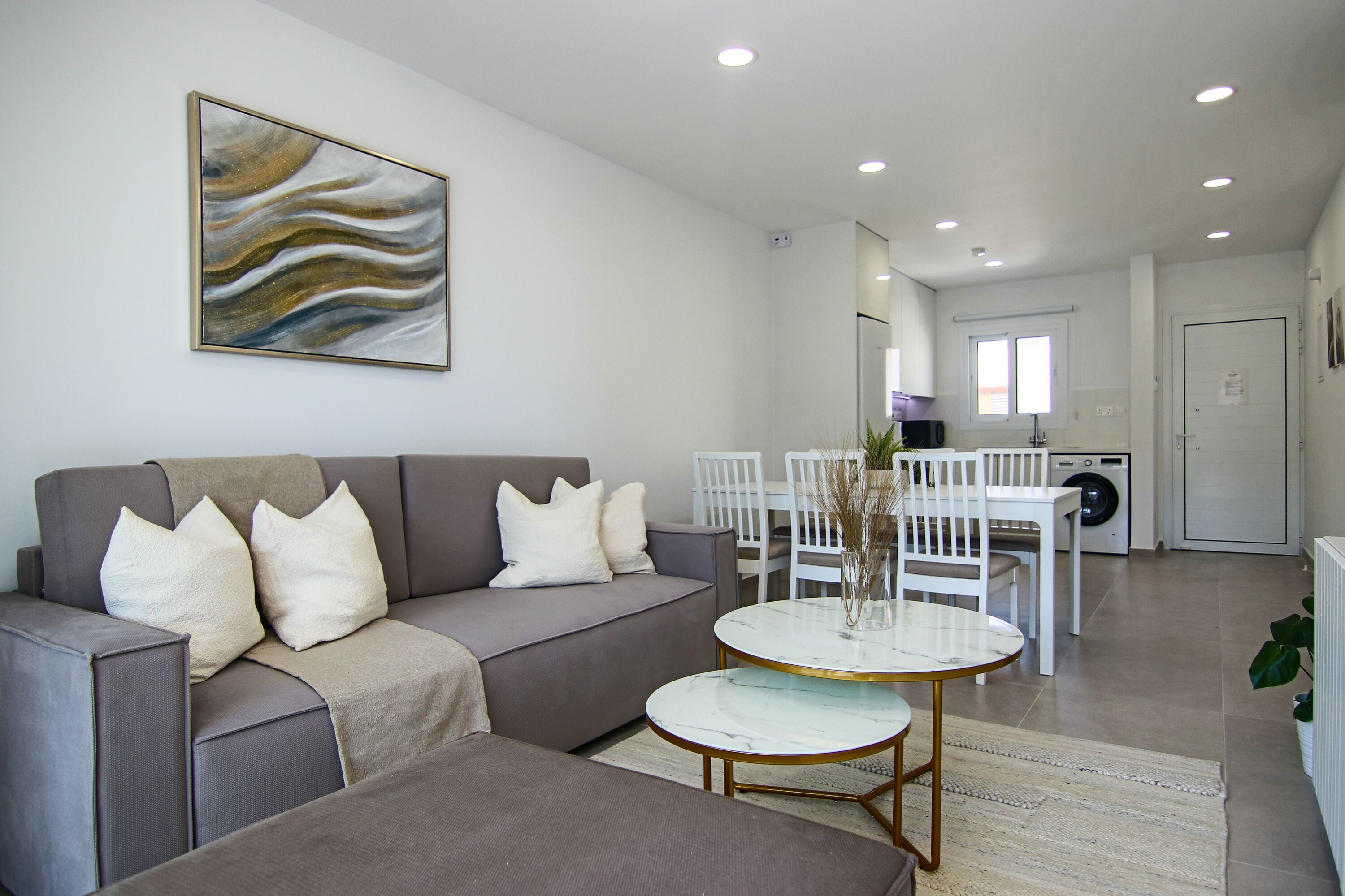 Un salon moderne avec un canapé gris, une table basse et un coin repas comprenant une table et des chaises.