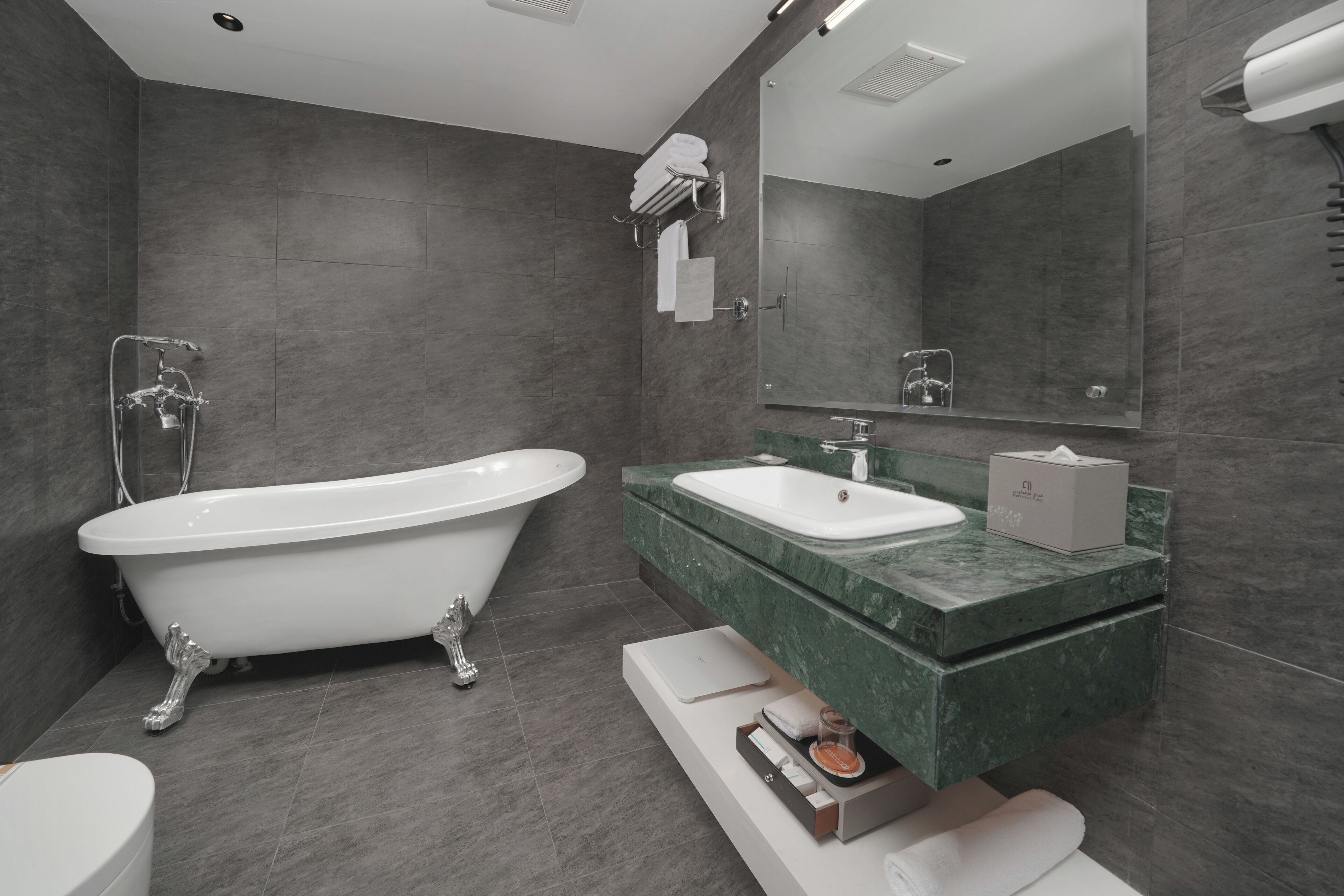 Un baño moderno con una bañera independiente, un lavabo con encimera de mármol y un espejo grande.