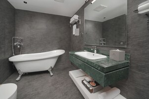 Un baño moderno con una bañera independiente, un lavabo con encimera de mármol y un espejo grande.