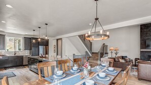 A spacious kitchen with dark cabinets, a central island, and a dining area set for six with blue and white tableware.