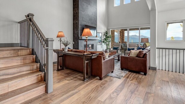 A spacious living area with a wooden staircase, a fireplace, and a view of the mountains.