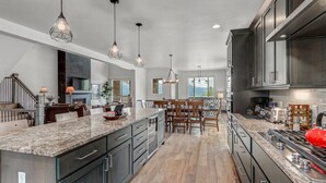 A spacious kitchen with granite countertops, dark cabinetry, and a central island.