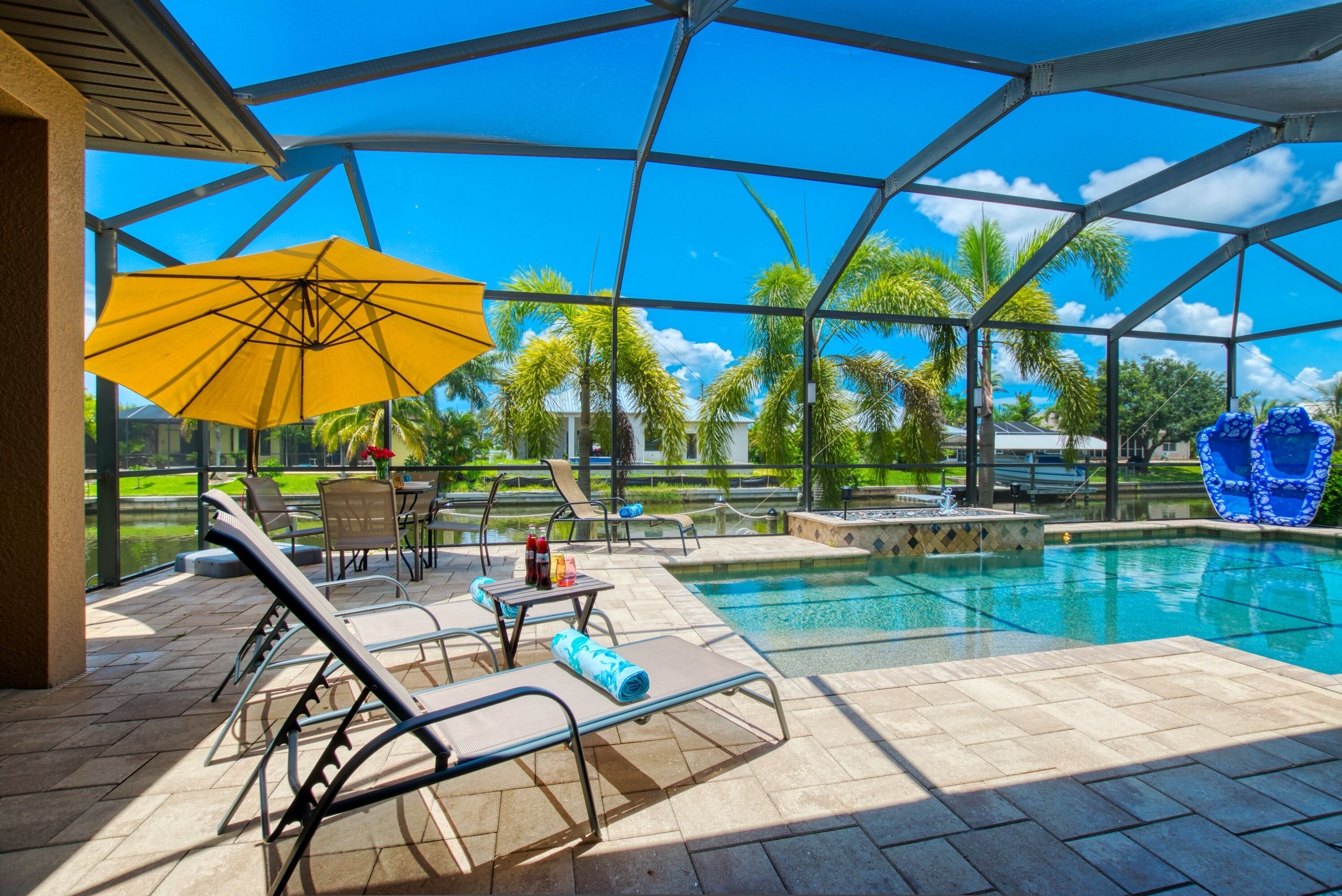 Un espace extérieur abrité comprenant une piscine, des chaises longues et des parasols.