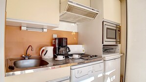A compact kitchenette with a sink, coffee maker, microwave, and a small oven.