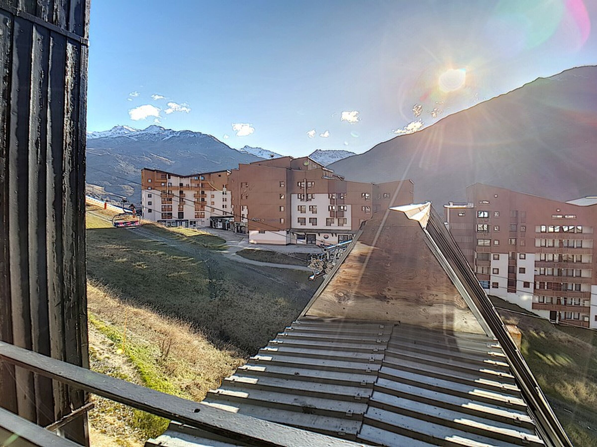 A ski resort with a ski lift, buildings, and mountains in the background.