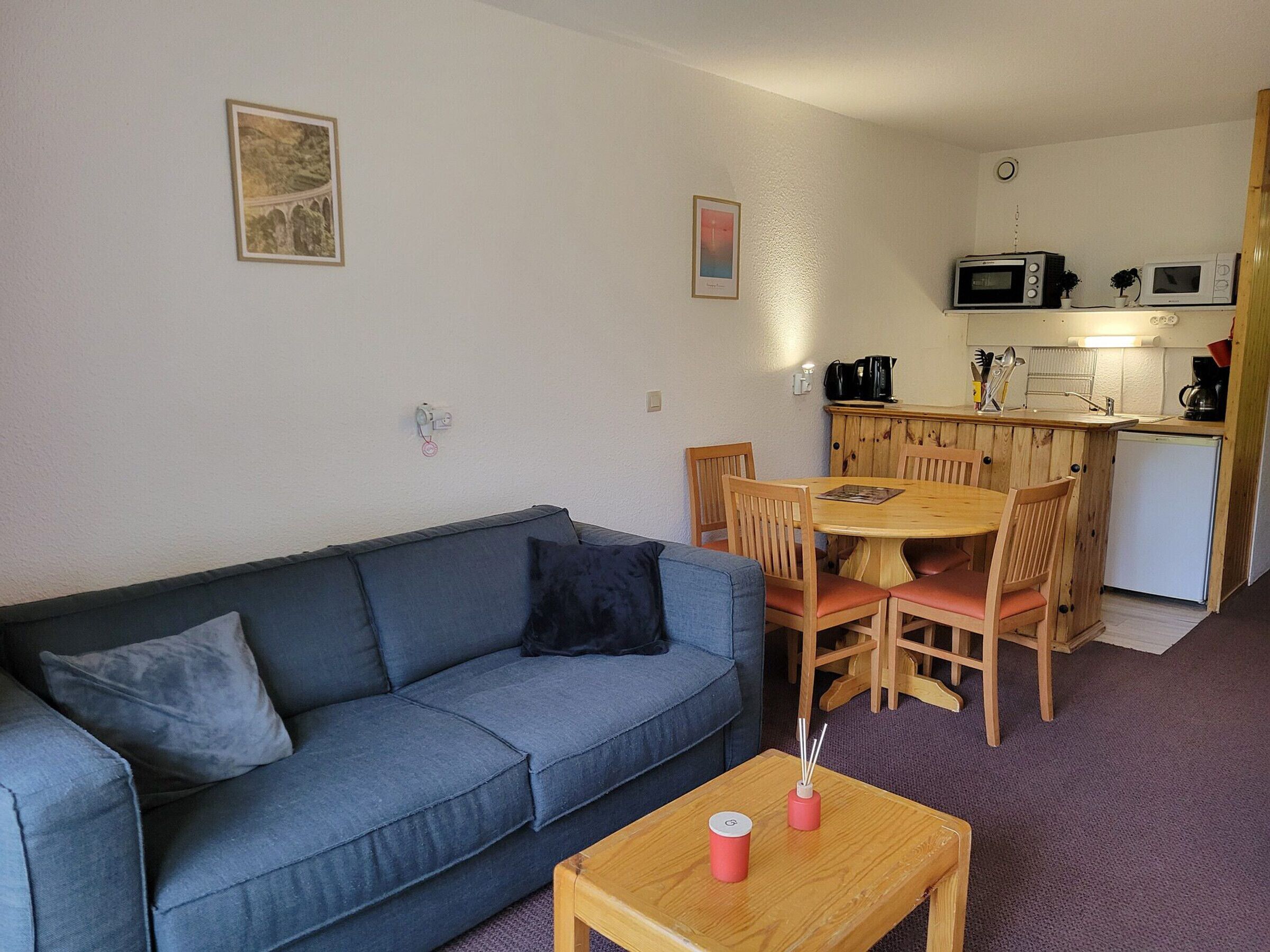 Un espace de vie compact comprenant un canapé, une table à manger et une kitchenette.