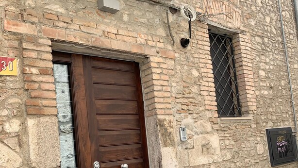 Un edificio de piedra con puerta de madera y una pequeña ventana con barrotes.