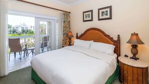 Una habitación de hotel con cama, mesita de noche, lámpara, silla y vista al exterior.