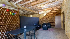 A covered outdoor seating area with a table and chairs, a wooden ceiling, and a lattice wall. - Cozy house in Daglan with fireplace and terrace (Daglan)