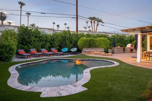 A backyard with a swimming pool, outdoor seating, and a barbecue area.