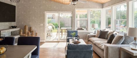 A spacious living area with a wooden ceiling, a dining area with a table and chairs, and a sofa set.