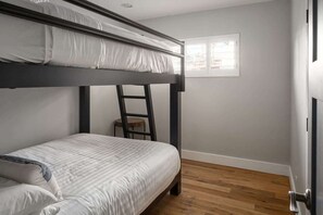 A bunk bed room with a ladder, a small table, and a window.