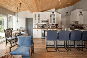 A modern kitchen with white cabinets, a central island, and bar stools.