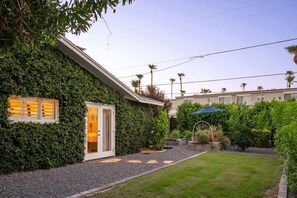 A house with a lush green ivy-covered exterior, a gravel pathway leading to a door, and a well-maintained lawn.