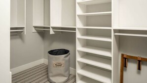 Ein weißer Schrank mit mehreren Regalen und einem grauen Wäschekorb mit der Aufschrift 'SELF SERVICE LAUNDRY'.