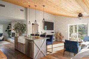 A spacious kitchen with a central island, pendant lighting, and a wooden ceiling.
