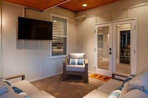 A cozy room with a television mounted on the wall, a cushioned chair, and a sliding glass door leading to another area. - Old Town Farm-to-Table: Harvest, Pool, Spa (Scottsdale)